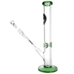 En grøn bong i glas med en højde på 40 cm præsenterer sig med en slank, cylindrisk form. Den har en bred, stabil fod, der sikrer balance. Glasset har en glat, transparent overflade med en let grøn nuancering. Der er en indbygget perkolator med flere små huller, og en skål til urter er placeret på siden.