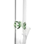 En grøn bong i glas med en højde på 40 cm. Den har en buet, cylindrisk skulpturform og en transparent overflade, der fremviser indholdet. Nederst er der en bred, stabil fod, der understøtter strukturen. En slangeformet rør med en krumning fører til en lille åbning. Der er detaljer som en indbygget perkolator og en skål til urter.