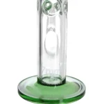 En transparent, grøn bong med en højde på 50 cm præsenterer sig med en glat, buet form. Den har en tyk, cylindrisk bund og en smalere hals, der afsluttes med en kroneformet åbning. En slange, der er monteret på siden, fører til en lille skål, mens en indvendig perkolator sikrer filtrering af røg. Overfladen har en let glans og er fri for synlige urenheder.