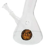 En 30 cm høj bong med en slank, cylindrisk form fremstår i klare, farverige nuancer. Den har et detaljeret mønster af spiraler og bølger, der skaber en dynamisk visuel effekt. Materialet er gennemsigtigt glas, som giver mulighed for at se den indre struktur. En afrundet krave og en dyb skål er synlige, samt en smal mundstykke.