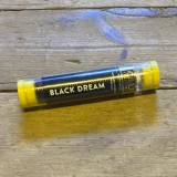 En sort glasflaske med en smal hals, der indeholder en væske med en dyb, mørk farve. Flasken har en minimalistisk etiket med hvid tekst, der angiver indholdet, og en sort låg, der passer tæt. Flaskens overflade har en glat og skinnende tekstur, mens etiketten har en mat finish, hvilket skaber en kontrast i materialerne.