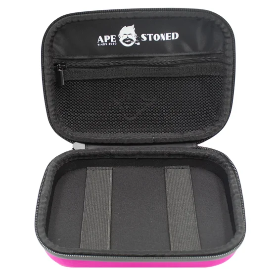 En klassisk pink telefonkasse præsenterer sig med en glat, blank overflade, der reflekterer lys. Kassen har afrundede kanter og en firkantet form, der skaber en harmonisk silhouette. Foran er der en let fremtrædende åbning til en telefon, mens der er diskrete ventilationshuller i bunden. Farven er ensartet, og det pink nuancerer fra lys til mørk, hvilket tilføjer dybde.