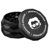 En sort hexagonal grinder med en diameter på 55 mm. Overfladen har en mat tekstur, der giver et stilrent udseende. Kanten er let afrundet, og der er små, præcist placerede huller til at sikre jævn kværning. Den øverste del har en let skruefunktion, og indvendigt er der skarpe tænder til effektiv maling af materialer.