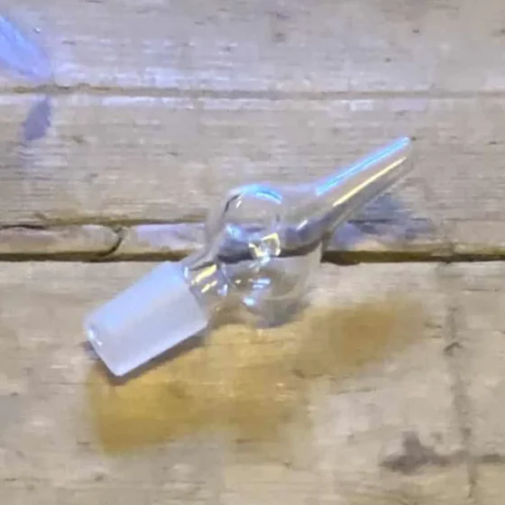 Mundstykket er fremstillet af klart glas og præsenterer en glat, gennemsigtig overflade. Det har en cylindrisk form med en let afrundet spids, der tilføjer en subtil elegance. Kanten er skarpt defineret, mens der er let buede former nær bunden. Ingen synlige dekorationer eller mønstre findes, hvilket giver et minimalistisk udtryk.