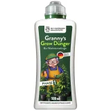 En transparent flaske med en grøn væske indeni. Flasken har en sort skruelåg og en etiket i hvid, grøn og sort med tekst og symboler. Etiketten viser et grønt blad og indeholder information om produktet. Flaskens form er cylindrisk, og den står på en neutral overflade, der fremhæver dens farver og design.
