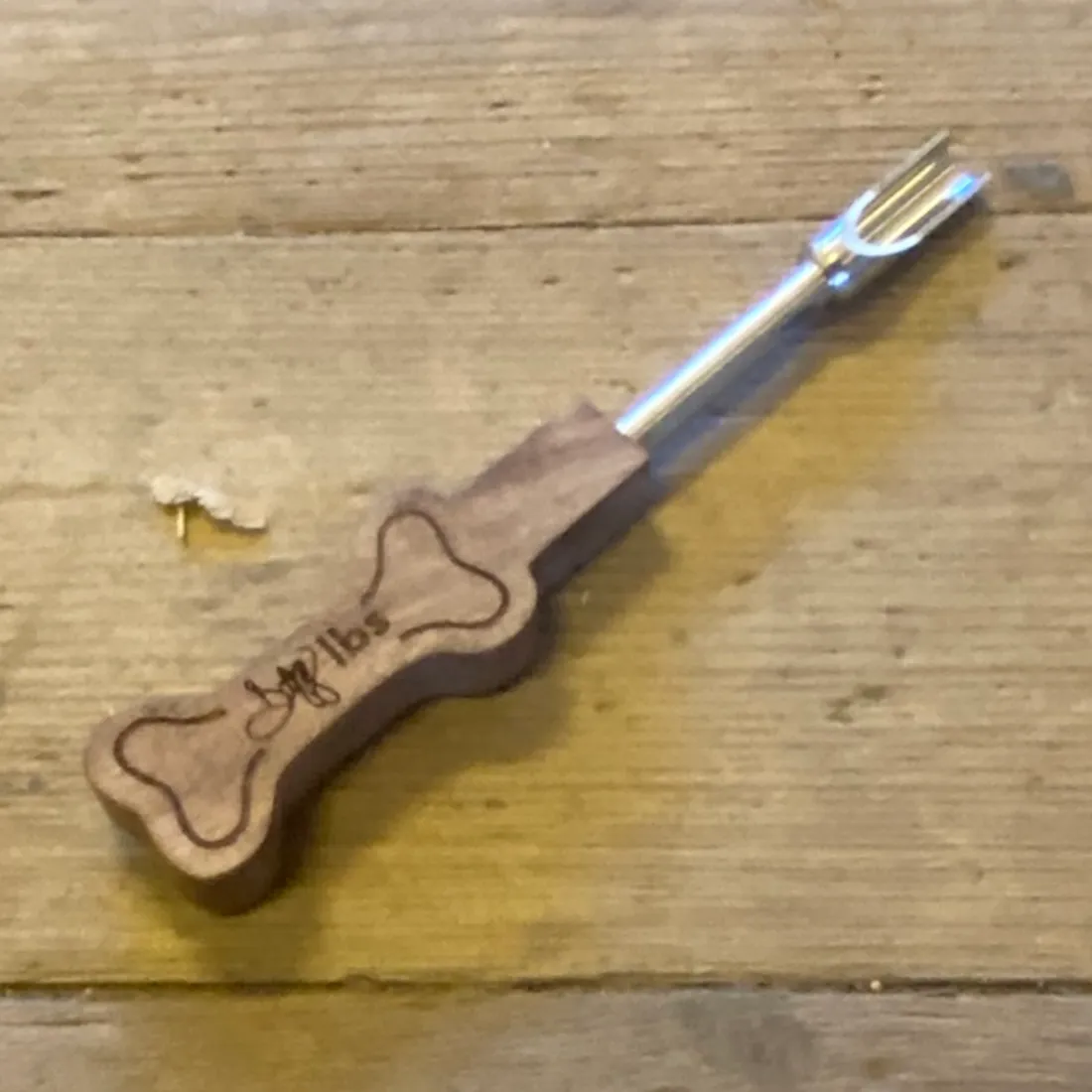 Dogg LBS Dabbing Kit med en sølvfarvet gaffelspids på et brunt træhåndtag med indgraveret omrids af et kødben.