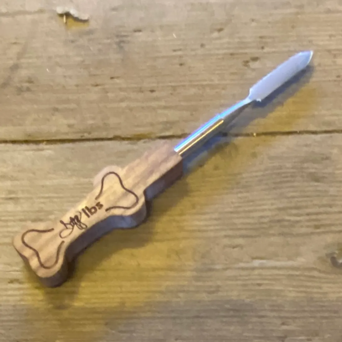 Dogg LBS Dabbing Kit med en flad, sølvfarvet spatelspids på et lysebrunt træhåndtag med indgraveret kødben.