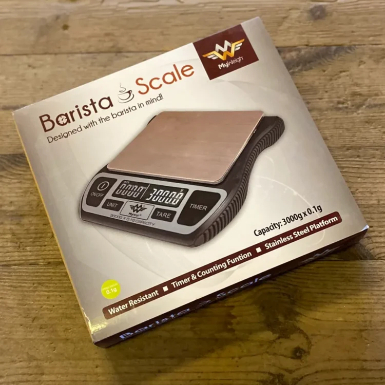 MyWeigh Barista Vægt 0,1-3000g i hvid æske med brunt "Barista Scale"-tryk og digitalt display vist på forsiden.