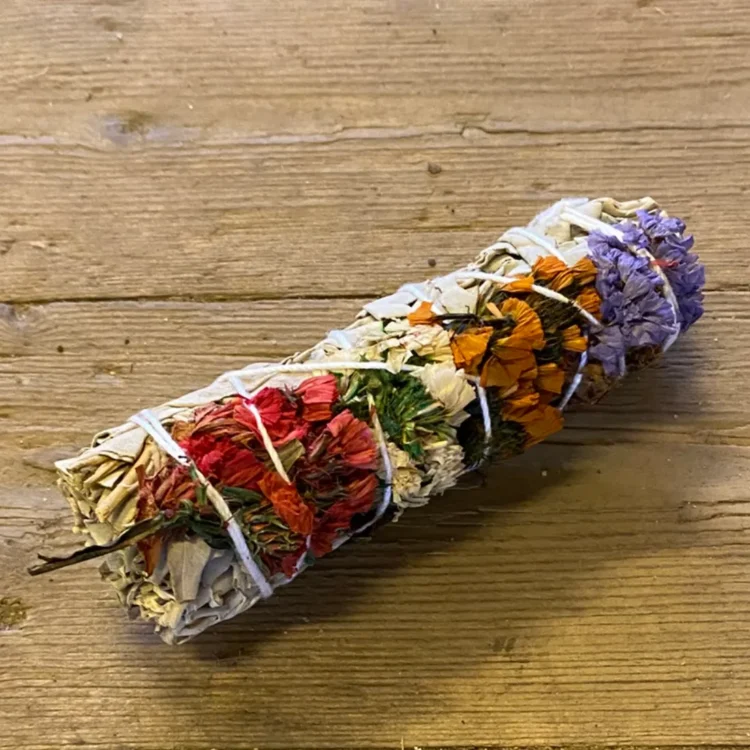 Smudge Stick Happy Spirit 10 cm med tørrede blade og røde, orange og lilla blomster bundet sammen med hvid snor.