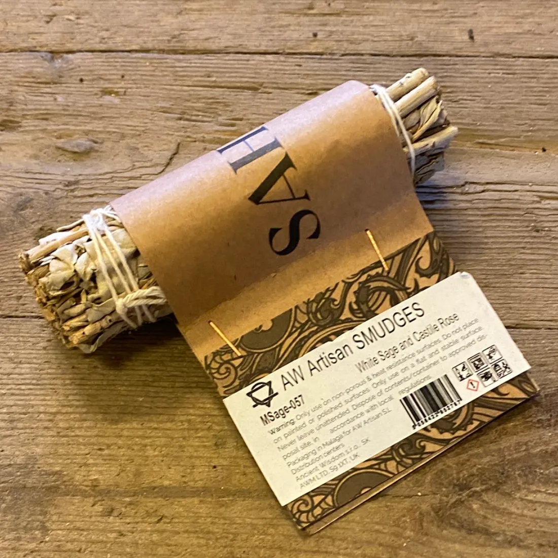Smudge Stick White Sage & Castile Rose 11 cm i brunt papiromslag med plantemotiv og hvid etiket med "AW Artisan SMUDGES".