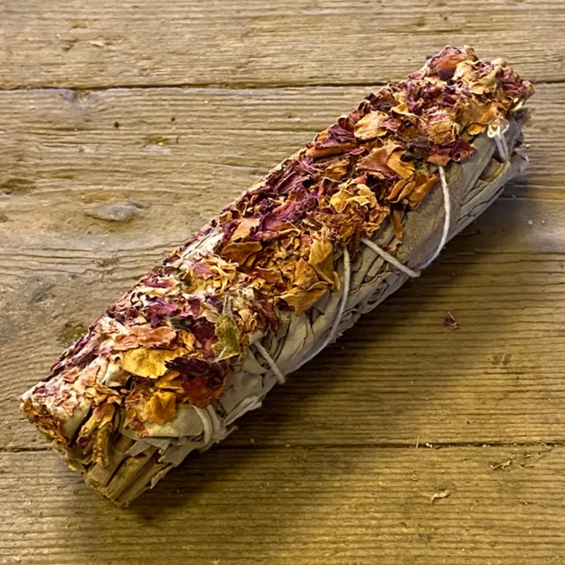 Smudge Stick White Sage & Castile Rose 11 cm med tørrede blade i hvid snor, dækket af orange og rødlilla rosenblade.