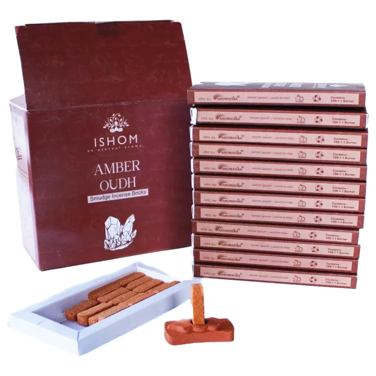 ISHOM Amber Wood Smudge Bricks 15 stk, brune røgelsesstykker i hvid bakke ved mørkerød æske med "ISHOM" trykt i hvidt.